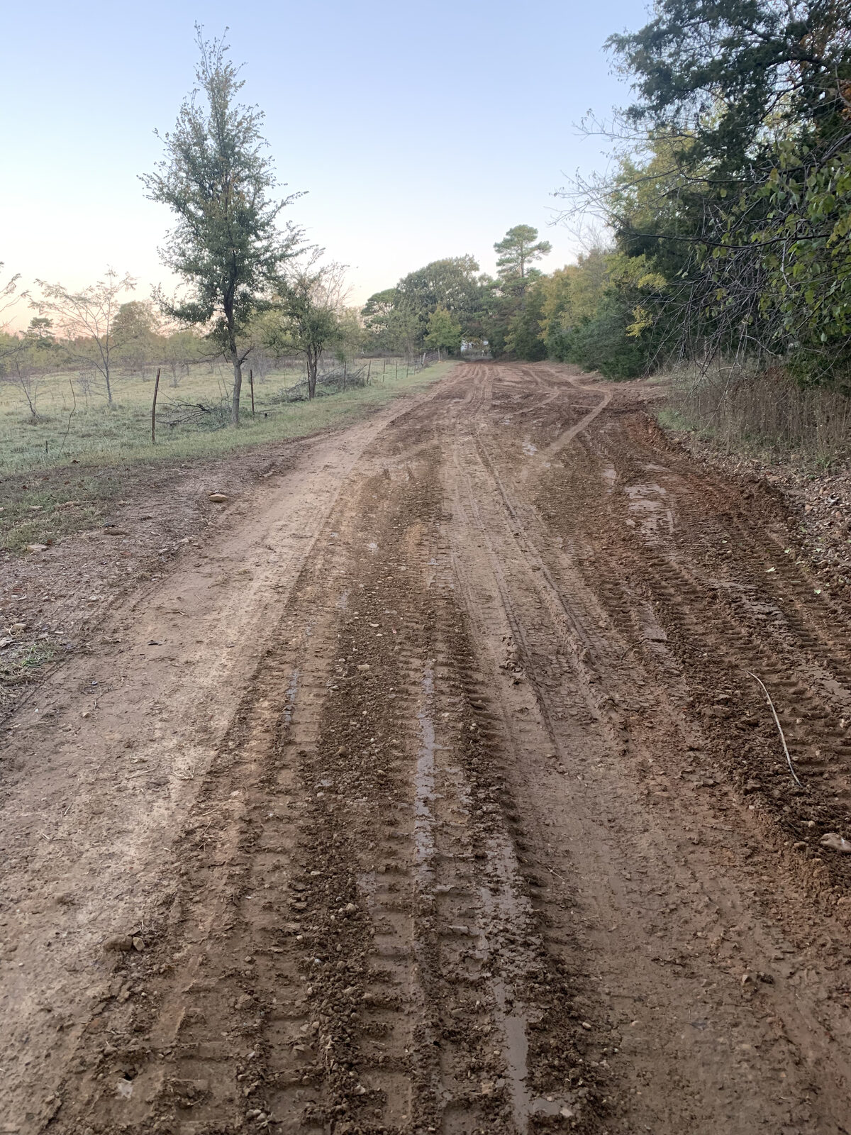 Muddy rutted dirt driveway before grading and gravel in Arkansas